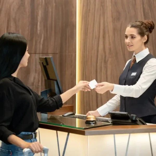 young-brunette-receptionist-uniform-standing-by-workplace-passing-plastic-card-one-guests-reception-counter-hotel-lobby